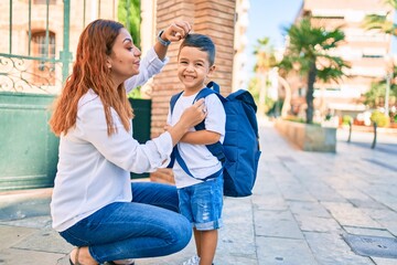Latin mother combing with hand her student boy at the city.