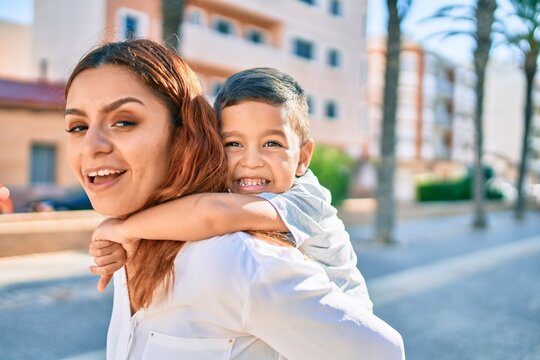 Adorable latin mother and son smiling happy hugging at the city.