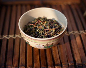 Closeup of a cup with leaves of Chinese tea on the table indoors.