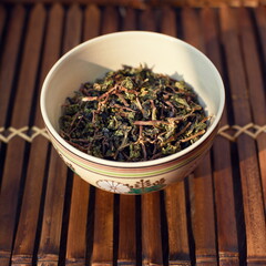 Fototapeta premium Closeup of a cup with leaves of Chinese tea on the table indoors.