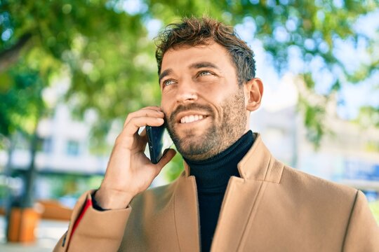 Handsome business man wearing elegant jacket using smartphone smiling happy outdoors
