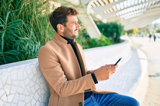 Handsome business man wearing elegant jacket using smartphone smiling happy outdoors