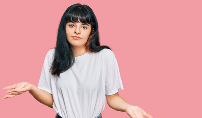 Young hispanic girl wearing casual clothes clueless and confused expression with arms and hands...