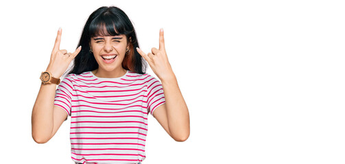 Young hispanic girl wearing casual clothes shouting with crazy expression doing rock symbol with hands up. music star. heavy music concept.