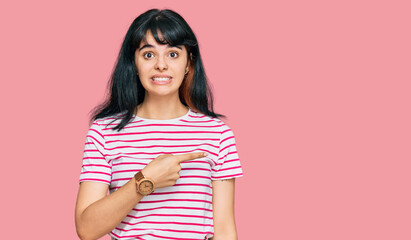 Young hispanic girl wearing casual clothes pointing aside worried and nervous with forefinger, concerned and surprised expression