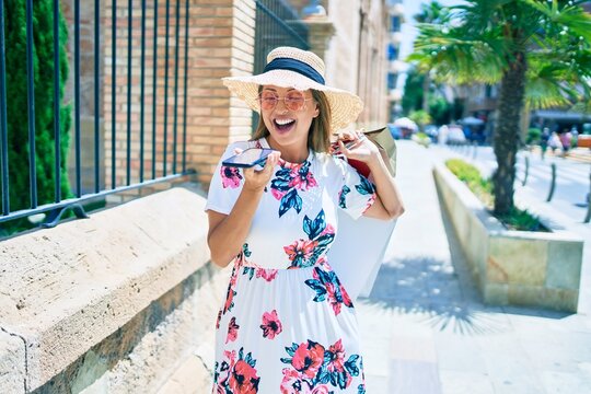 Middle age woman holding shopping bags and using smartphone at the city