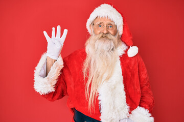 Old senior man with grey hair and long beard wearing traditional santa claus costume showing and pointing up with fingers number four while smiling confident and happy.