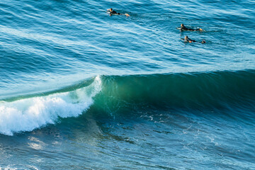 Surfers waiting to catch the wave in the Pacific Ocean at Puertecillo spot in Chile. Amazing waves for surfing in an awe wild scenery photographed with a tilt shift lense for generating a 3D effect
