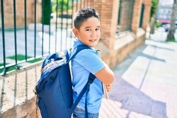 Fototapeta premium Adorable student boy smiling happy holding book at street of city.