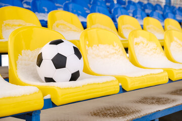 Soccer ball placed on snowy seats on stadium tribune in winter 