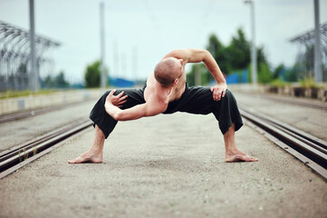 Fototapeta na wymiar Young caucasian male practicing yoga on the city streets