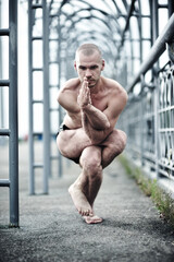 Fototapeta na wymiar Young caucasian male practicing yoga on the city streets