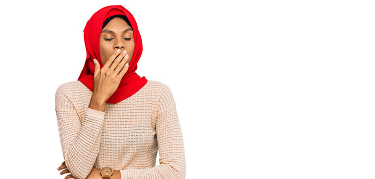 Young african american woman wearing traditional islamic hijab scarf bored yawning tired covering mouth with hand. restless and sleepiness.