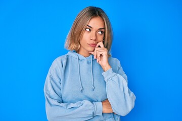 Beautiful caucasian woman wearing casual sweatshirt serious face thinking about question with hand on chin, thoughtful about confusing idea