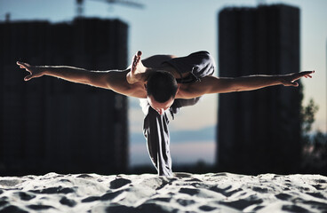 Caucasian man practicing yoga at night in the city.