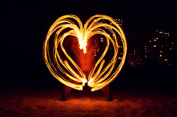 Fire dancer drawing figures by fire at night.