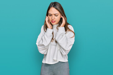 Young brunette woman wearing casual turtleneck sweater covering ears with fingers with annoyed expression for the noise of loud music. deaf concept.