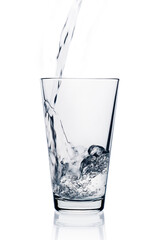 In a transparent glass on a white background pouring water from the bottle.