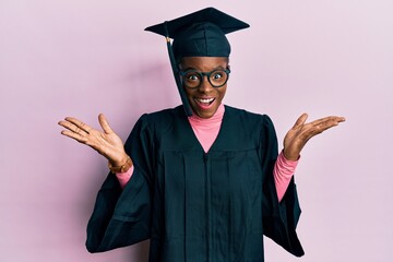 Young african american girl wearing graduation cap and ceremony robe celebrating crazy and amazed...