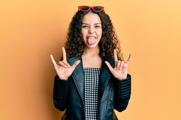 Teenager hispanic girl doing rock gesture sticking tongue out happy with funny expression.