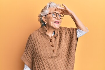 Senior grey-haired woman wearing casual clothes and glasses very happy and smiling looking far away...