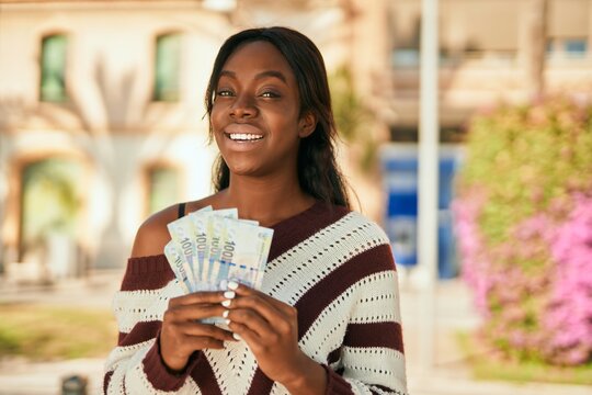 Young african american woman smiling happy holding south africa rands at the park.