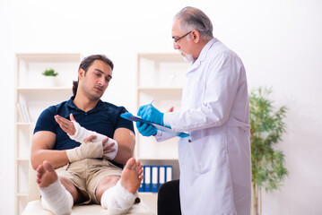 Fototapeta premium Young injured man visiting old doctor traumatologist