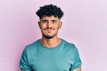 Young arab handsome man wearing casual clothes puffing cheeks with funny face. mouth inflated with air, crazy expression.