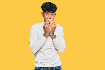 Young arab man wearing casual winter sweater laughing and embarrassed giggle covering mouth with...