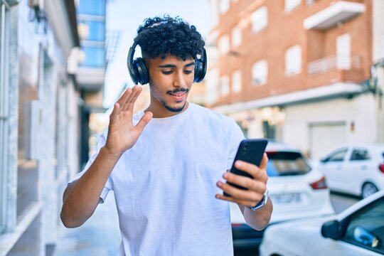 Young arab man smiling happy doing video call using smartphone walking at city.