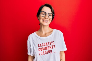 Fototapeta premium Young brunette woman with short hair wearing sarcastic comments loading t-shirt looking positive and happy standing and smiling with a confident smile showing teeth