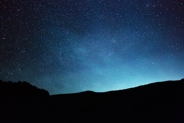 Starry sky over the mountains at night in summer.