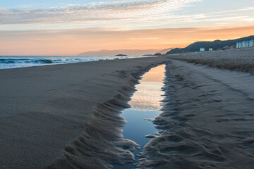 A small pool on sandy beach of the Mediterranean Sea at sunrise