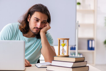 Young male student preparing for exams in time management concep