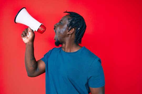 Young handsome african american man screaming using megaphone over isolated red background