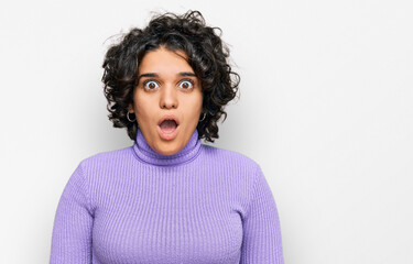 Young hispanic woman with curly hair wearing casual clothes afraid and shocked with surprise and amazed expression, fear and excited face.