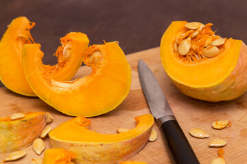 Cutting pumpkin wedges on wooden board. Cooking healthy vegetarian food at home