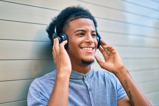 Young african american man listening to music using headphones at the city.