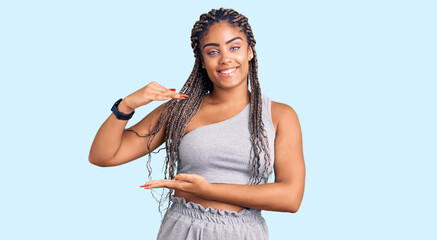 Young african american woman with braids wearing sportswear gesturing with hands showing big and large size sign, measure symbol. smiling looking at the camera. measuring concept.