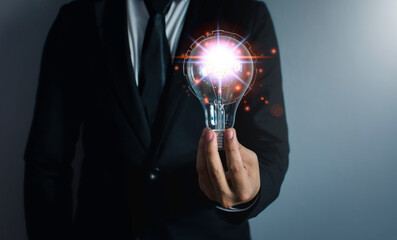 Hand of businessman holding light bulb, innovative technology. Mixed media, digital concepts.