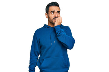 Young hispanic man wearing casual clothes looking stressed and nervous with hands on mouth biting...