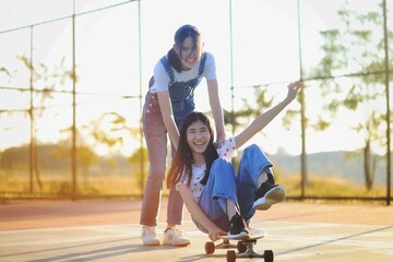 Asian Girl Friends Playing With Skateboard. Laughing And Fun Together.