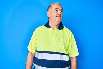 Senior grey-haired man wearing reflective t shirt looking to side, relax profile pose with natural...