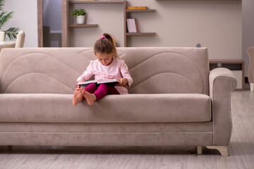 Obraz premium Small girl reading book at home