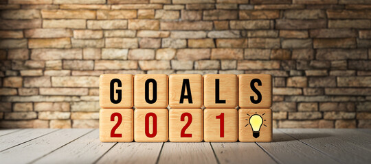 wooden cubes with the message GOALS 2021 on wooden surface in front of a brick wall