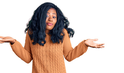 Beautiful african american woman wearing casual  sweater clueless and confused expression with arms...