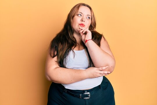Plus size caucasian young woman wearing casual clothes thinking concentrated about doubt with finger on chin and looking up wondering