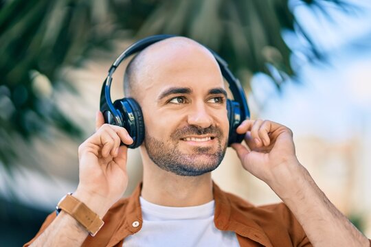 Young hispanic bald man smiling happy using headphones at the city