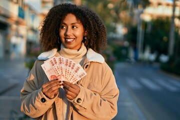 Young african american woman smiling happy holding new taiwan dollar at the city.