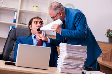 Old male boss and his young male assistant in bullying concept